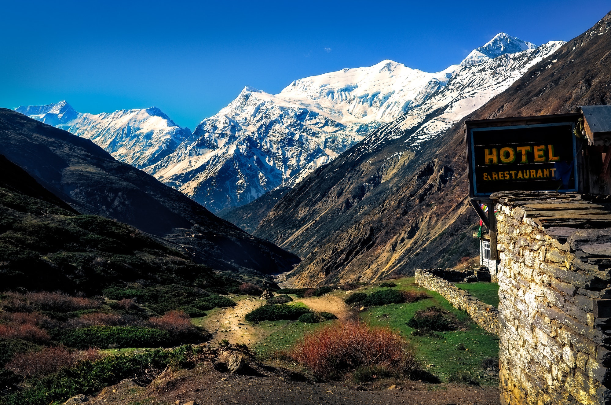 Mountain landscape view with local stone hut and hotel sign, Himalayas