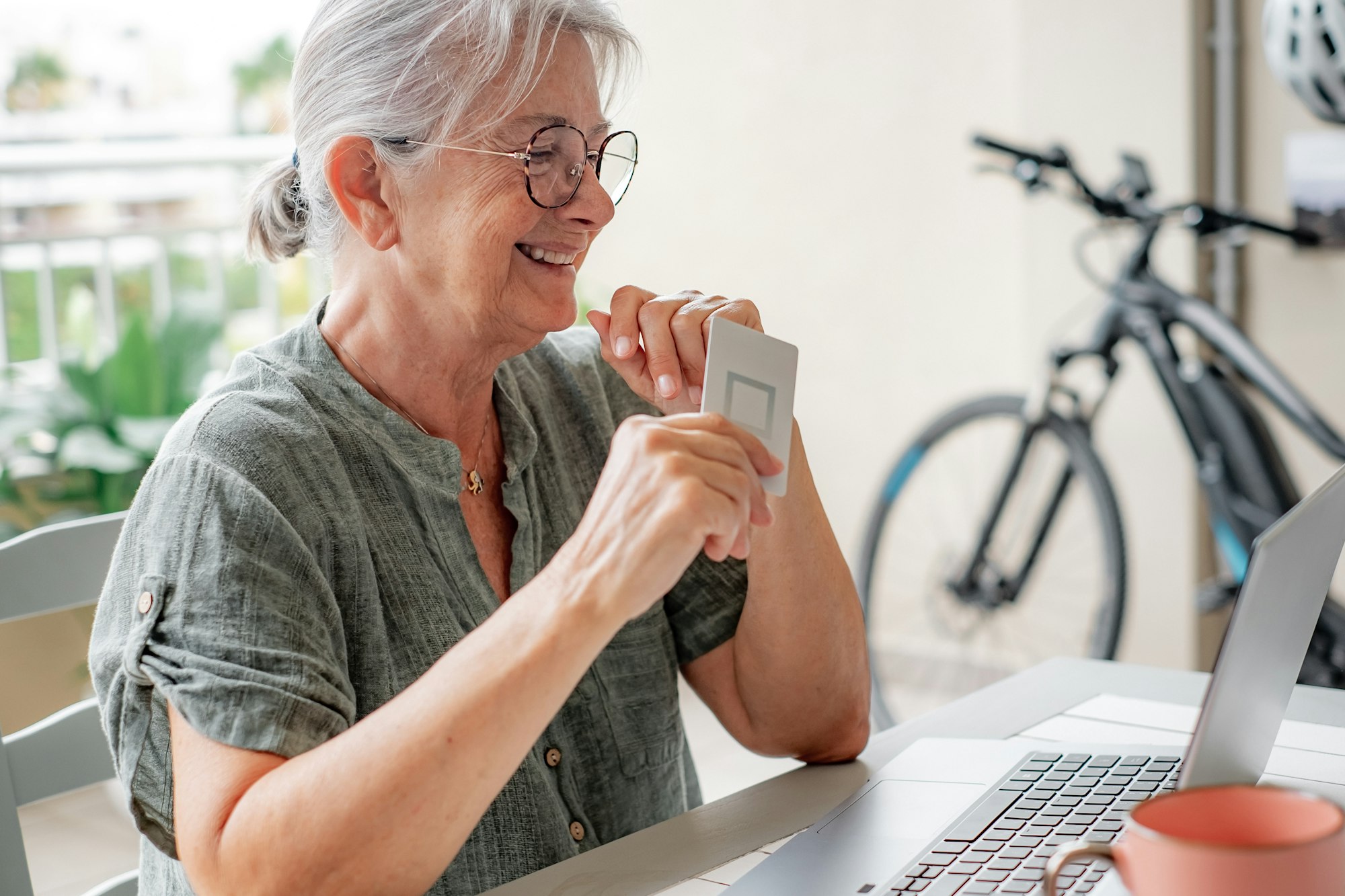 Online shopping concept. Smiling senior woman using laptop sitting at table doing e-commerce purchas